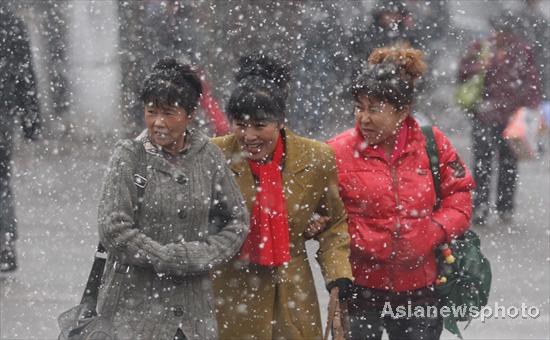 Three women walk through snow showers in Harbin, Northeast China&apos;s Heilongjiang province, Oct 25, 2010.