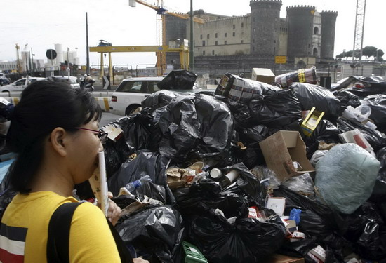 A woman covers her mouth near a pile of garbage in downtown Naples Oct 22, 2010. [China Daily/Agencies] 
