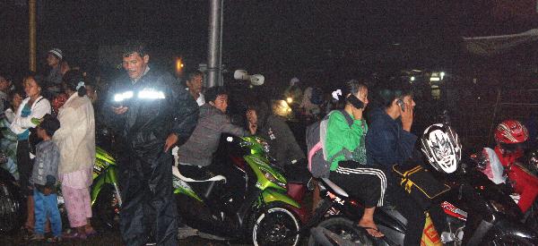 People try to reach their relatives by mobile phone as they flee to higher ground in Padang, West Sumatra, on October 25, 2010. [Xinhua]