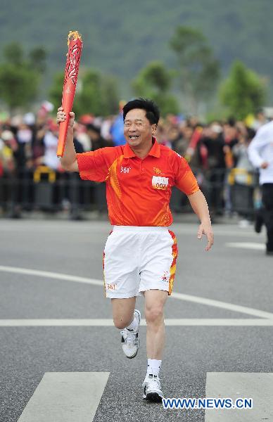 The second torchbearer Zheng Gang holds the torch aloft during the torch relay for the 16th Asian Games in Shaoguan City, south China's Guangdong Province, Oct. 27, 2010. (Xinhua/Liang Xu) 