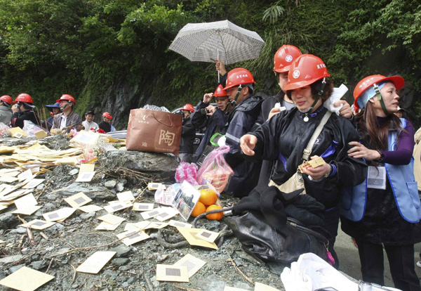 A relative of a victim from a bus carrying tourists from the Chinese mainland hit by a landslide during Typhoon Megi, offer incense paper at the scene of the accident on Suao-Hualien Highway in Taiwan Oct 27, 2010. The families of the 19 missing mainland tourists arrived in Taiwan on Monday night. The mudslide killed nine people with about 26 people still missing. [China Daily/Agencies]