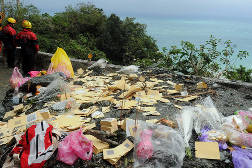 Relatives of victims from a bus carrying tourists from the Chinese mainland hit by a landslide during Typhoon Megi, offer incense paper at the scene of the accident on Suao-Hualien Highway in Taiwan Oct 27, 2010. [China Daily/Agencies]