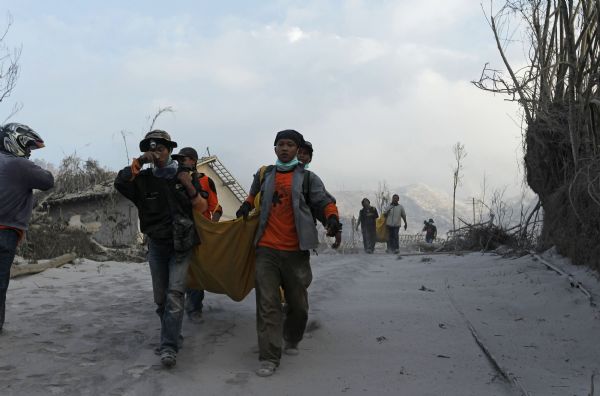 Volunteers carry the bodies of victims of the Mount Merapi eruption at Kinarrejo village in Sleman, near the ancient city of Yogyakarta October 27, 2010. One of Indonesia's most active volcanoes spewed out clouds of ash and jets of searing gas on Wednesday in an eruption that has killed at least 29 people. [Xinhua]
