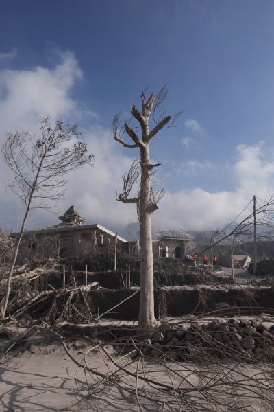 Volunteers walk near a burnt house after Mount Merapi erupted at Kinahrejo village in Sleman, near the ancient city of Yogyakarta, October 27, 2010. One of Indonesia's most active volcanoes spewed out clouds of ash and jets of searing gas on Wednesday in an eruption that has killed at least 29 people. [Xinhua]