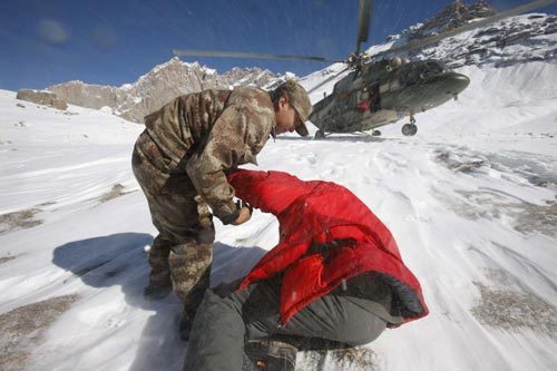 A rescuer helps an engeer to get up and run for the helicopter during a rescue in Tianshan Mountains area near Baicheng county of Aksu prefecture in Northwest China's Xinjiang autonomous region, Oct 27, 2010. [Photo/Xinhua] 