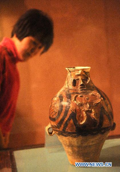 A woman looks at an ancient painted pottery replica in the Liuwan Painted Pottery Museum at Liuwan Village of Ledu County, northwest China's Qinghai Province, Oct. 24, 2010. The museum houses some 40,000 ancient painted potteries, making it the largest of the kind in China. 