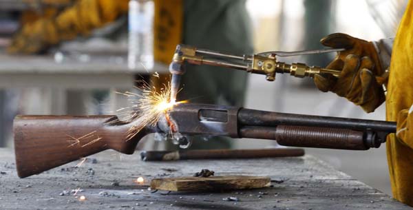 A police officer uses a welding torch to break down a rifle for disposal in Panama City. [China Daily/Agencies] 