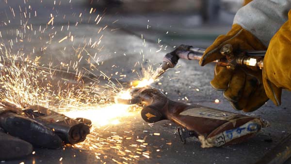 A police officer uses a welding torch to break down a rifle for disposal in Panama City. [China Daily/Agencies] 