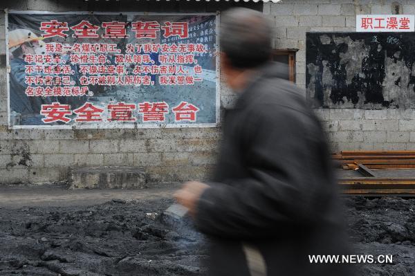 A worker walks past a poster with the slogan reminding the safety in production outside the flooded Dapo coal mine in Machang Town of Puding County under Anshun City, southwest China&apos;s Guizhou Province, Oct. 28, 2010. The Dapo coal mine was flooded on Oct. 27, leaving 12 workers dead and another injured. [Xinhua] 