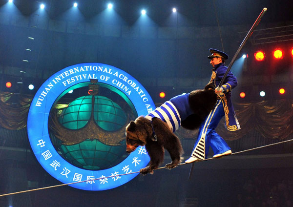 A Russian acrobat performs tightrope walking with a bear during the international art festival in Wuhan, Oct 31, 2010. [Xinhua]