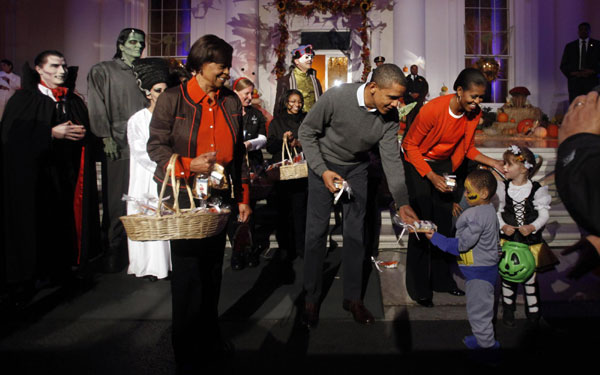 US President Barack Obama (C), first lady Michelle Obama (R) and her mother Marian Robsinon (L) participate in a Halloween trick-or-treat on the steps of the North Portico of the White House in Washington, Oct 31, 2010. [China Daily/Agencies]