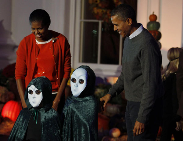 US President Barack Obama and first lady Michelle Obama pose with two children dressed as aliens as they participate in a Halloween trick-or-treat on the steps of the North Portico of the White House in Washington, Oct 31, 2010. [China Daily/Agencies]