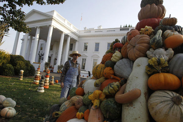 An actor dressed as a farmer looks at a display of pumpkins and gourds on the North Lawn of the White House on Halloween night in Washington, Oct 31, 2010. [China Daily/Agencies]