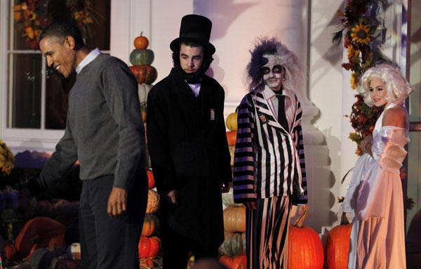 Halloween participants dressed as former US President Abraham Lincoln (2nd L), Beetlejuice and Marilyn Monroe watch as President Barack Obama greets others in a Halloween trick-or-treat event on the steps of the North Portico of the White House in Washington, Oct 31, 2010. [China Daily/Agencies]