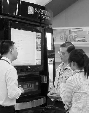 A technician (left) introduces functions of Travelers Convenience's vending machines to consumers in Beijing. [China Daily]