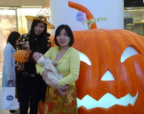 A mother and her baby take photos with a staffer at Wangfujing shopping mall in Beijing on Halloween. Mall staffers wore Halloween costumes with pumpkin lamps.[Photo/CFP]