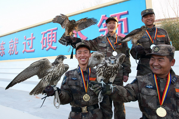 Soldiers who have won medals in a bird-repelling competition pose for photos with their falcons in Shenyang, Oct 31, 2010. [Xinhua]