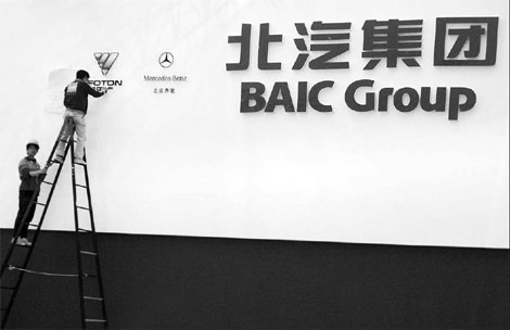 Workers prepare a bulletin board of BAIC Group before the Beijing Auto Show in April. The Beijing-based carmaker has been consolidating its resources to strengthen its brand. [China Daily]