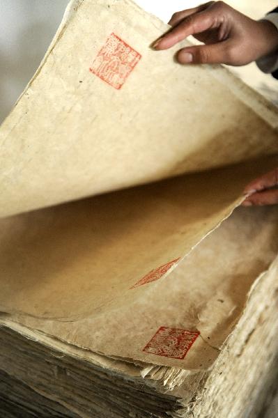 A museum staff member shows handmade paper in Longting Town, northwest China's Shaanxi Province, on Oct. 27, 2010. The 73-year-old Ma Lingzhong and 60-year-old Wang Qingxia were two of the few who could make paper in the way Cai Lun, the inventor of paper, did 1,900 years ago. They were invited to show the papermaking process at Cai Lun Paper Culture Museum in Longting Town. [Xinhua photo]