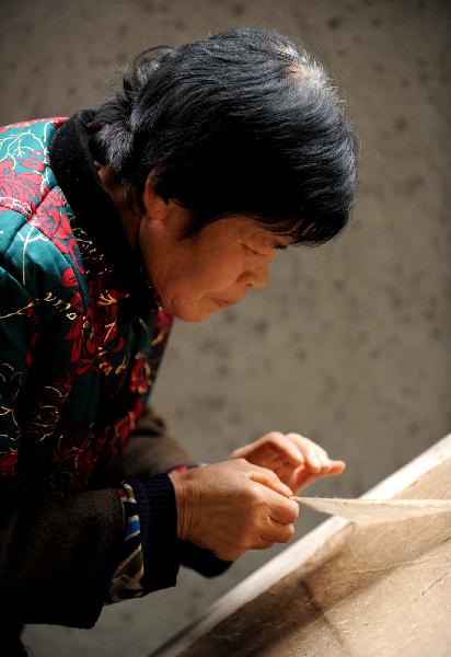 Wang Qingxia dries newly made paper in Longting Town, northwest China's Shaanxi Province, on Oct. 27, 2010. The 73-year-old Ma Lingzhong and 60-year-old Wang Qingxia were two of the few who could make paper in the way Cai Lun, the inventor of paper, did 1,900 years ago. They were invited to show the papermaking process at Cai Lun Paper Culture Museum in Longting Town. [Xinhua photo] 