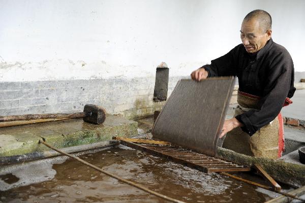Ma Lingzhong processes papermaking materials in Longting Town, northwest China's Shaanxi Province, on Oct. 27, 2010. The 73-year-old Ma Lingzhong and 60-year-old Wang Qingxia were two of the few who could make paper in the way Cai Lun, the inventor of paper, did 1,900 years ago. They were invited to show the papermaking process at Cai Lun Paper Culture Museum in Longting Town. [Xinhua photo] 