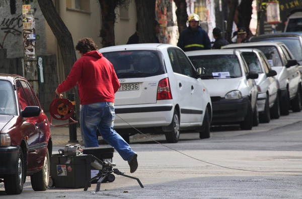 A Greek police explosives expert runs a cable before a controlled explosion of a suspicious package at a courier company some 300 metres from the Presidential residence in Athens November 2, 2010. [China Daily/Agencies] 