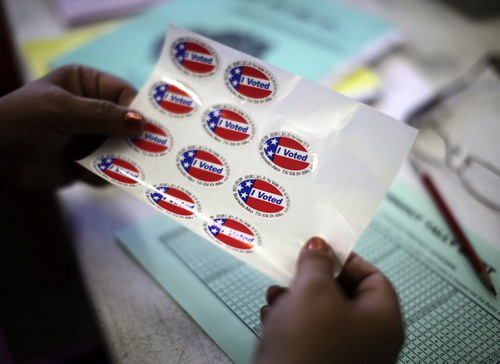  An election worker hands out voting stickers at a polling place on Venice Beach in Los Angeles, California, November 2, 2010. [China Daily/Agencies] 