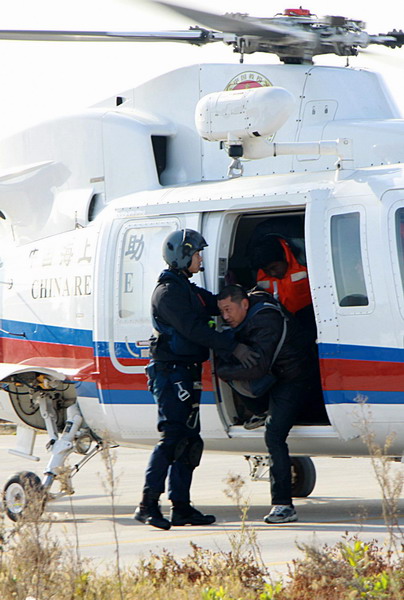 Rescued crew members of a stranded freighter walk out of a helicopter with the help of rescue workers at a parking lot in Weihai, East China's Shandong province, Nov 2, 2010. 