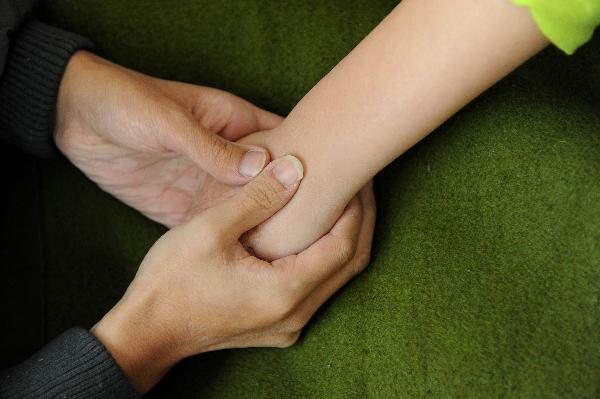 Dong Zhijun (L) holds tight a hand of his fiancé Yuan Wanyu after the first surgery for the disfigured girl is finished in Shenyang, capital of northeast China&apos;s Liaoning Province, Oct. 19, 2010. [Xinhua]