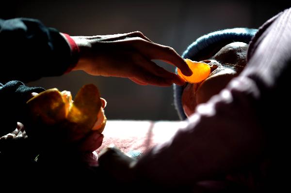 Dong Zhijun feeds his fiancé Yuan Wanyu (R) with orange as Wanyu, feeling uncomfortable in the eyes, lies in bed for a rest in Tai&apos;an, northeast China&apos;s Liaoning Province, Oct. 26, 2010. [Xinhua] 