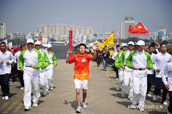 The 78th torchbearer Liang Shaofeng (C) runs with the torch during the torch relay for the 16th Asian Games in Yangjiang, south China's Guangdong Province, Nov. 2, 2010. (Xinhua/Liang Xu)