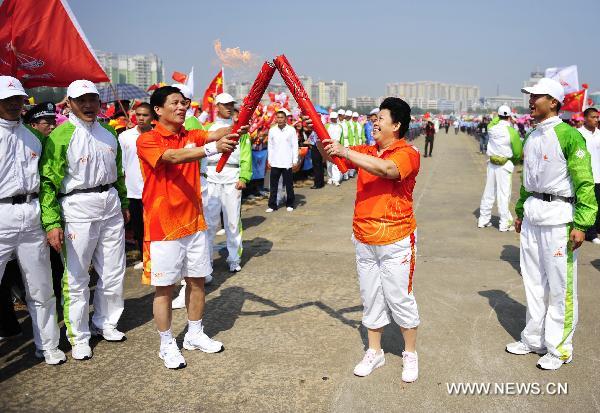 The 79th torchbearer Jiang Chunyan (R, Front) passes the flame to the 80th torchbearer Mo Zhangde during the torch relay for the 16th Asian Games in Yangjiang, south China's Guangdong Province, Nov. 2, 2010. (Xinhua/Liang Xu) 