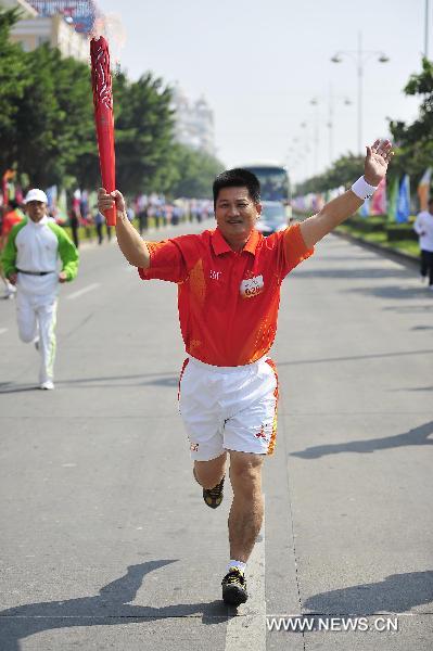 The 26th torchbearer Huang Maisheng runs with the torch during the torch relay for the 16th Asian Games in Yangjiang, south China's Guangdong Province, Nov. 2, 2010. (Xinhua/Liang Xu)