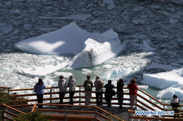 A group of tourists watch the ice blocks that emerge from the Perito Moreno Glacier, the most famous and stunning at Glacier National Park, opposite the Magallanes Peninsula, 78 kilometers away from the city of El Calafate, Argentina, on Nov. 2, 2010. 