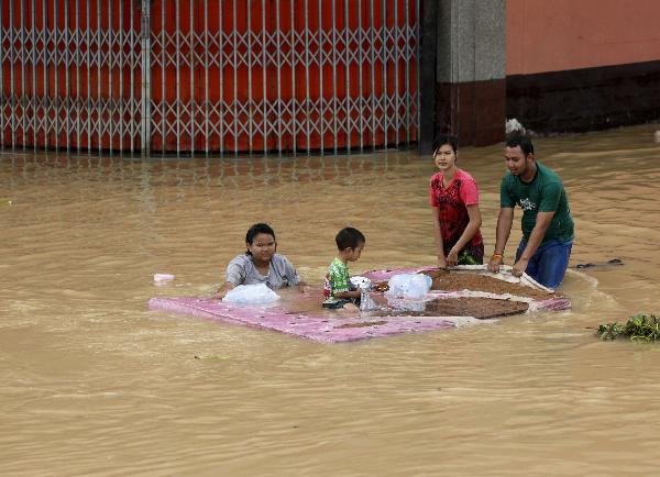 Residents push a mattress that their son is sitting on through a flood in Hat Yai district, Songkhla province south of Bangkok November 3, 2010. Transport and communications were severed and tourists stranded on Wednesday after southern Thailand&apos;s worst floods in a decade forced flight cancellations and left a bustling city in deep water. [Xinhua/Reuters]