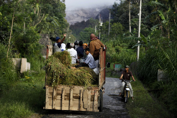 Villagers ride on a truck as they head to their village, Sidorejo in Klaten near the ancient city of Yogyakarta, as Mount Merapi spews smoke November 3, 2010. 