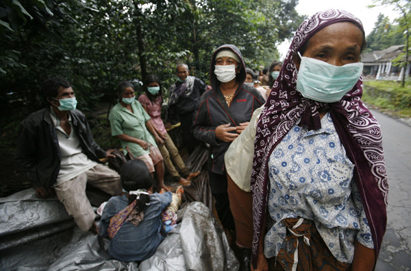Villagers wearing masks stand on a street after fleeing from their village in Sidorejo in Klaten of the Indonesia central Java province November 3, 2010. 