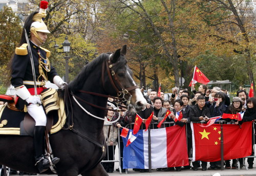 Fans wave Chinese national flags to welcome Chinese President Hu Jintao and his wife Liu Yongqing upon their arrival on the French Avenue des Champs Elysees in Paris on Th ursday. [China Daily/Agencies]