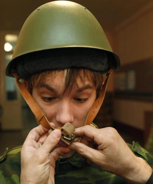 An officer helps a boy to put on a helmet during a 24-hour training session at a military division in Russia&apos;s Siberian city of Krasnoyarsk.[China Daily/Agencies]