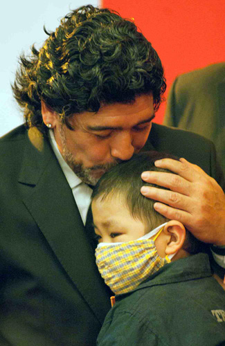 Argentine soccer legend Diego Maradona kisses a young Chinese cancer patient during a ceremony endorsing him as an ambassador for the China Red Cross Foundation in Beijing, Nov 4, 2010. [Xinhua]