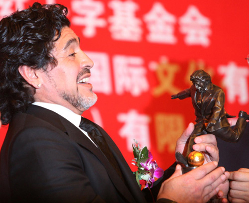 Maradona accepts a bronze statue of himself from the China Red Cross Foundation during a ceremony endorsing him as China&apos;s charity ambassador in Beijing, Nov 4, 2010. [Xinhua]