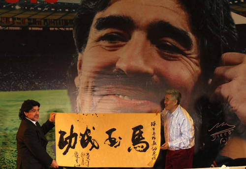 Maradona accepts Chinese calligraphy works from Chinese comedian Zhao Benshan during a charity dinner in Beijing, Nov 4, 2010. [Xinhua]