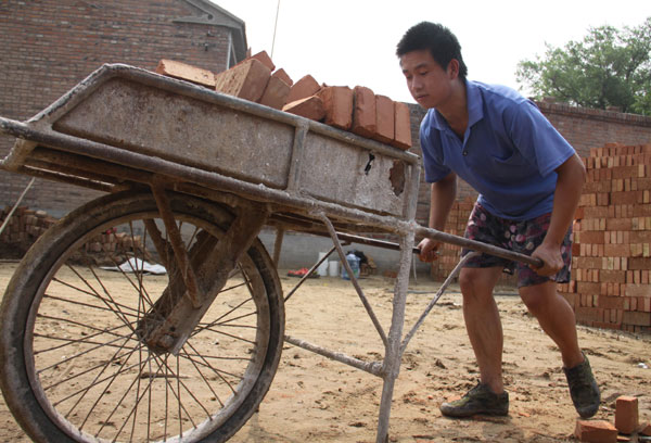 Zhang Heng, who enrolled at Nanjing-based Hohai University this summer, transports bricks on a construction site in his hometown, a small village in Cangzhou city of Hebei province, on July 23. He works there to make money for his tuition fees. Provided to China Daily    