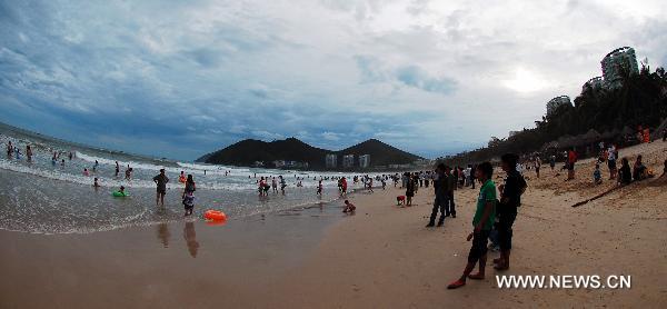 Photo taken on July 21, 2010 shows visitors enjoying themselves on a beach in Sanya of south China's Hainan Province. Sanya, a famous international tourist destination, was awarded as one of the '2010 China's Best Leisure Cities' jointly by the Leisure and Vacation Branch Association of China Tourism Association, National Leisure Standardization Technical Committee and batches of authoritative tourism institutes and companies on Nov. 6, 2010. [Xinhua/Jiang Tieying]