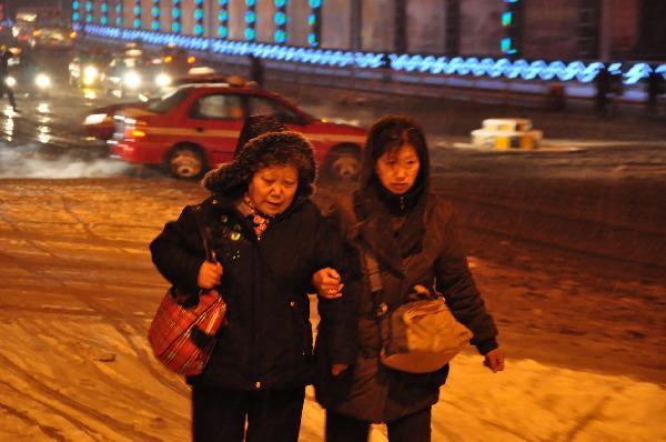 People walk in the snow in Mudanjiang, northeast China&apos;s Heilongjiang Province, Nov. 7, 2010. A cold front was sweeping the northern parts of China, causing snowfall or sleet and making the temperature drop in the areas. [Xinhua] 