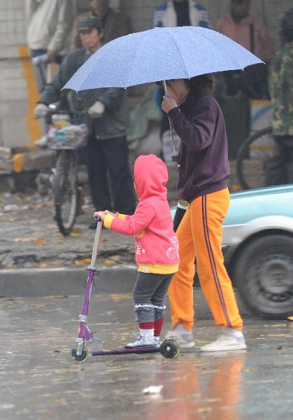 People walk in the rain in Dalian, a coastal city in northeast China&apos;s Liaoning Province, Nov. 7, 2010. A cold front was sweeping the northern parts of China, causing snowfall or sleet and making the temperature drop in the areas. 