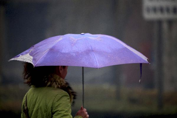 A pedestrian holds an umbrella on a street in Jilin City of northeast China&apos;s Jilin Province, Nov. 7, 2010. A cold front was sweeping the northern parts of China, causing snowfall or sleet and making the temperature drop in the areas. 