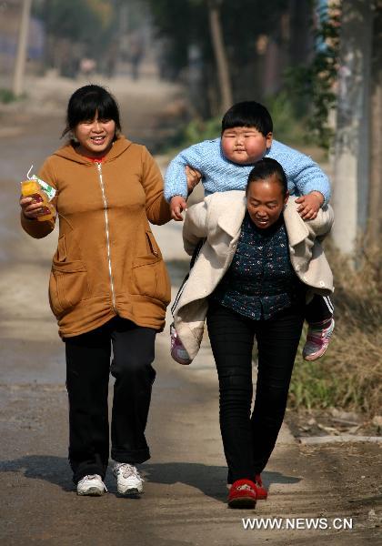 Fan Sijia goes home on the back of her grandma, with the escort of her mother in Dongniu Village of Yuncheng City, north China's Shanxi Province, on Nov 4, 2010.