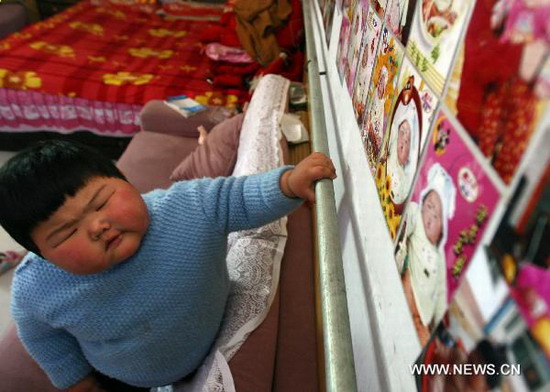 Fan Sijia looks at her photos at home in Dongniu Village of Yuncheng City, north China's Shanxi Province, on Nov 4, 2010. [Photo/Xinhua] 