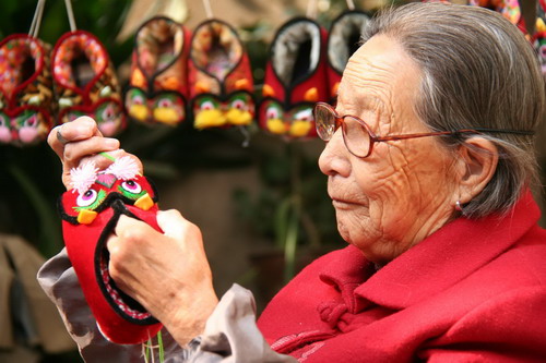 An elderly woman prepares a pair of tiger-like shoes made by hand in time for winter in Tancheng town, Linyi city of China&apos;s east Shandong province on Nov 7, 2010. As 2010 is the Year of the Tiger in Chinese lunar calendar, handmade tiger shoes are very popular among villagers as people believe the shoes are comfortable, warm, but more importantly, lucky.[Xinhua]